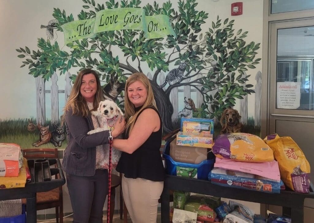 women holding white dog