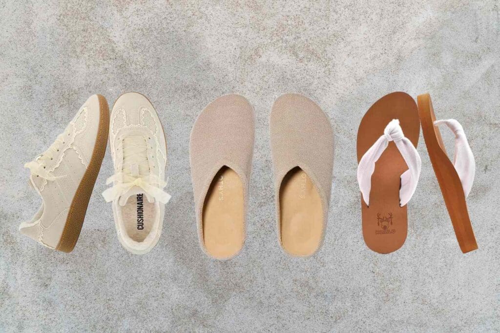 A row of shoes including sneakers slippers and flipflops arranged on a stone surface