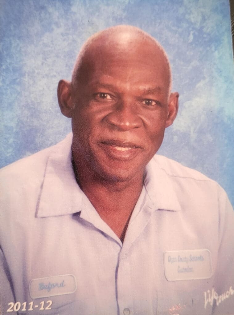 Smiling man in blue uniform shirt.