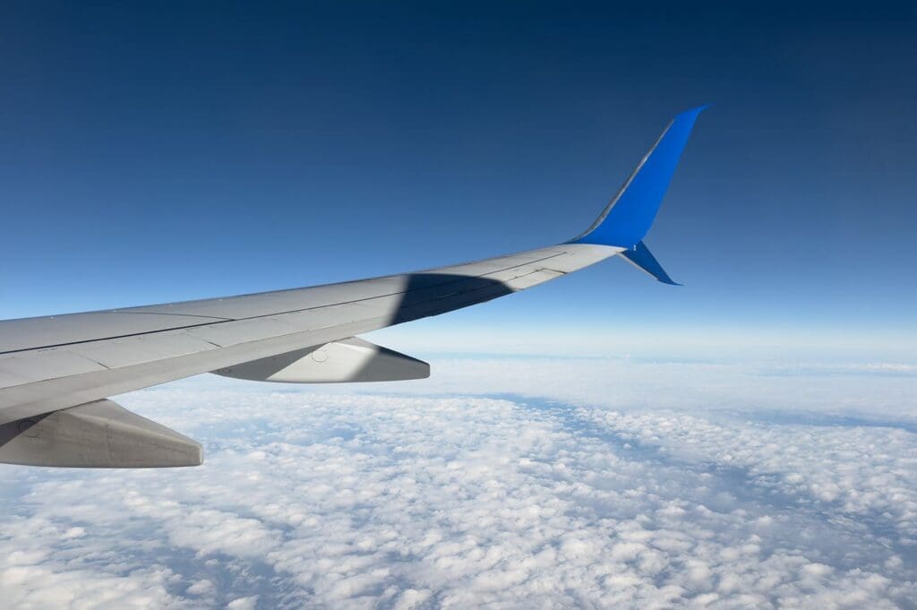 Google Flights Says the Cheapest Day to Book Airfare Is a Myth—Here’s What Really Matters An airplane wing flying above a cloudy sky