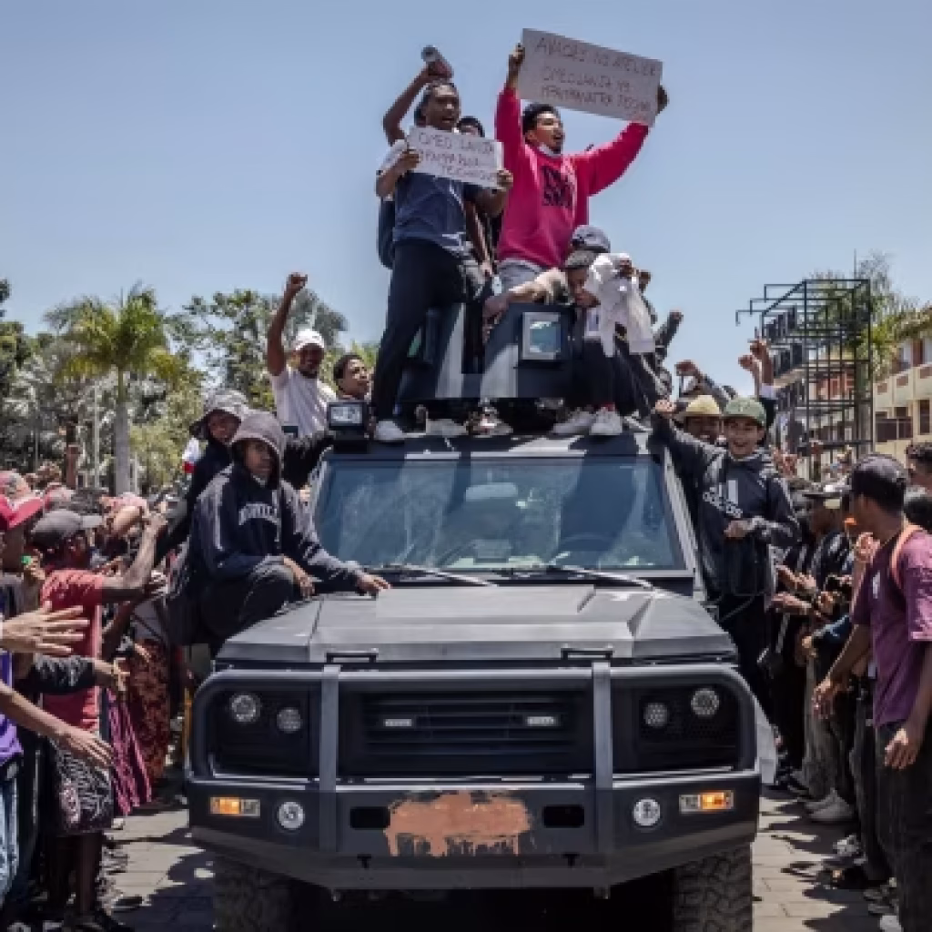 Protesters ride on an army patrol vehicle in Antananarivo as they chant anti-government slogans on Monday