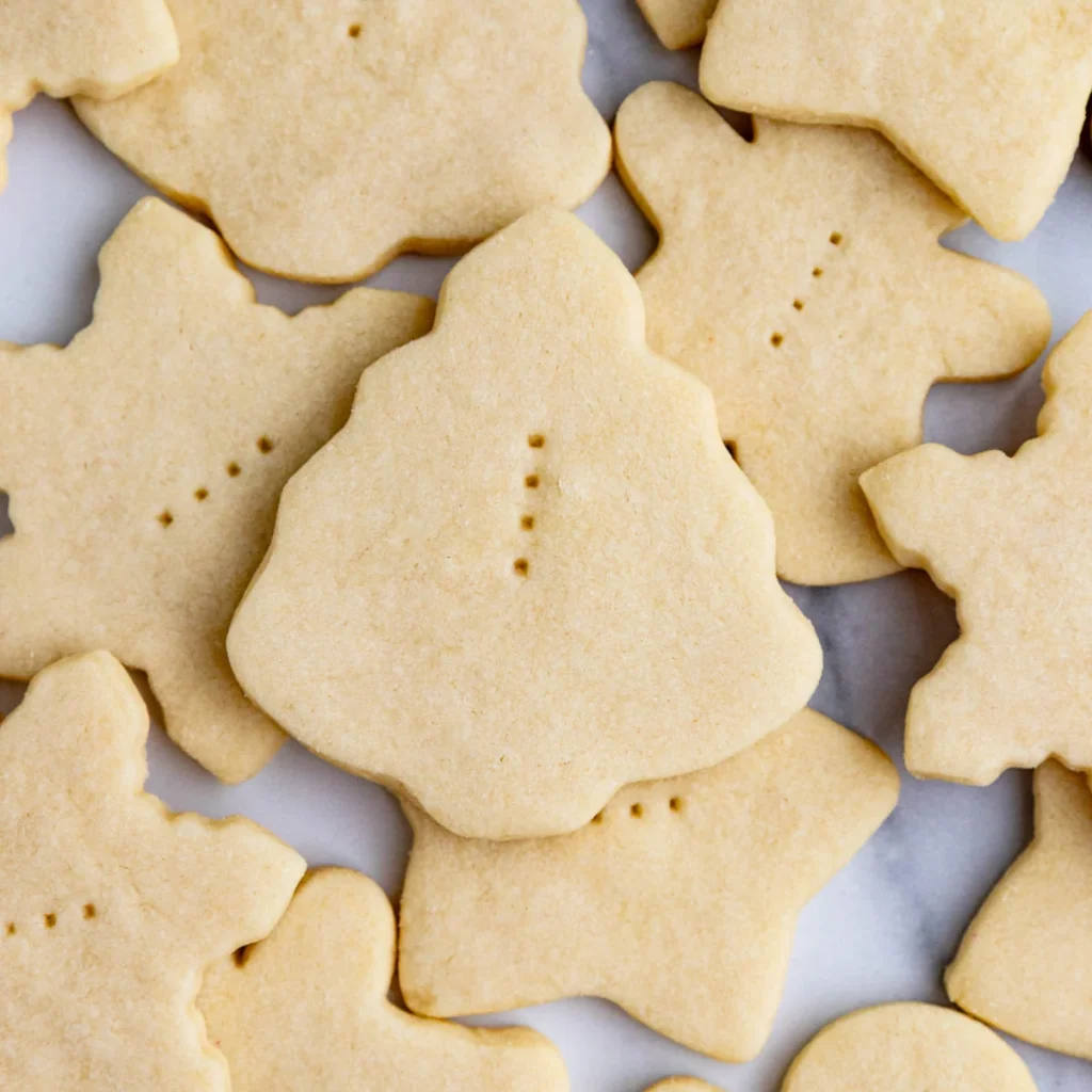 Baked shortbread cookies in various Christmas cookie cutter shapes arranged on a board