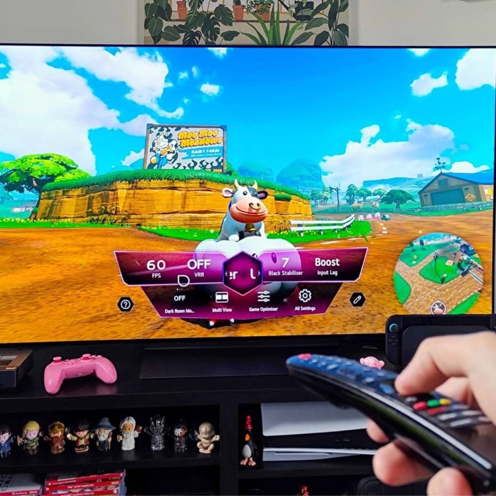 Hand holding remote in front of LG OLED C4 TV with Mario Kart World gameplay on screen.