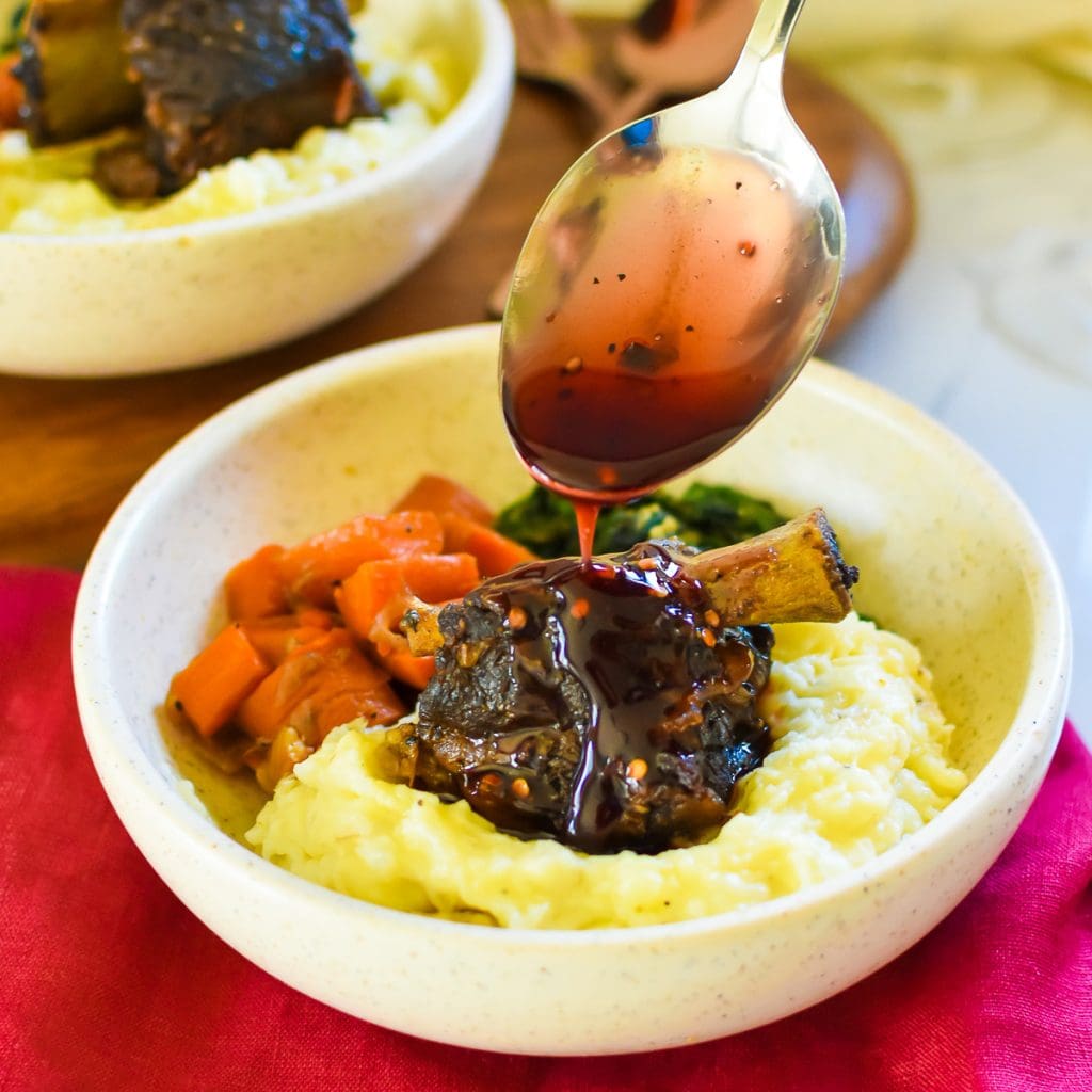 45 Valentine’s Day Supper Recipes to Take Pleasure In in your home brown hand pouring sticky pomegranate glaze over braised short rib with fluffy mashed potatoes.