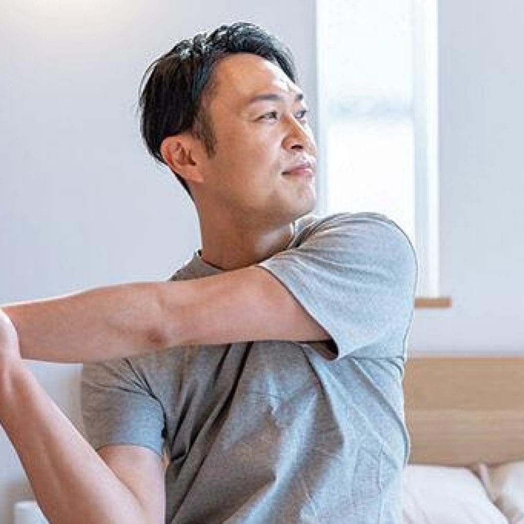 Man stretching his arm indoors.