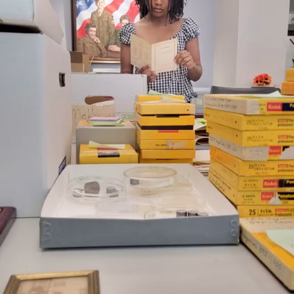 Ariana Taylor examines a document. Boxes of archive material are laid on a table in front of her.