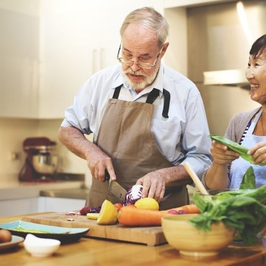 Senior couple chopping produce in their kitchen