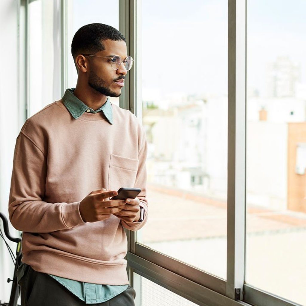 young man in glasses looks out the window