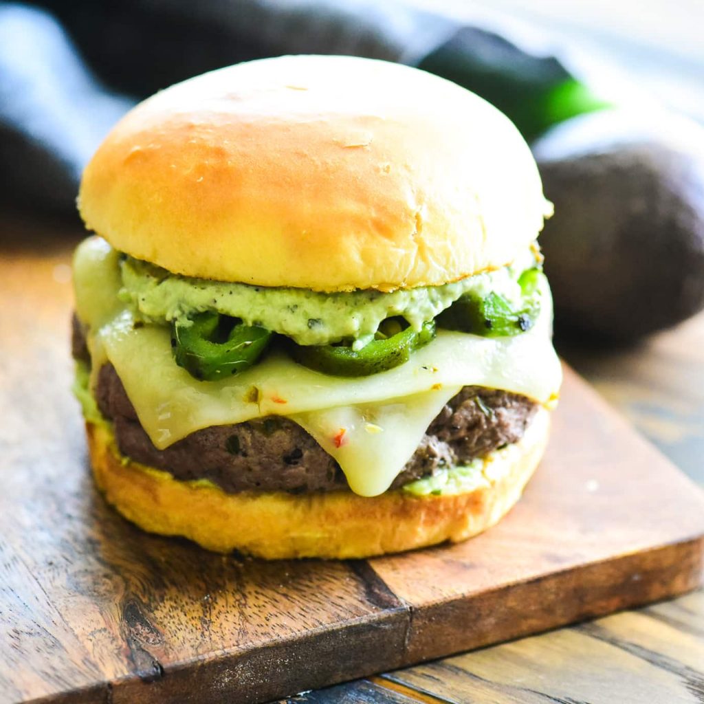 Juicy cheeseburger with avocado slices on a soft bun.