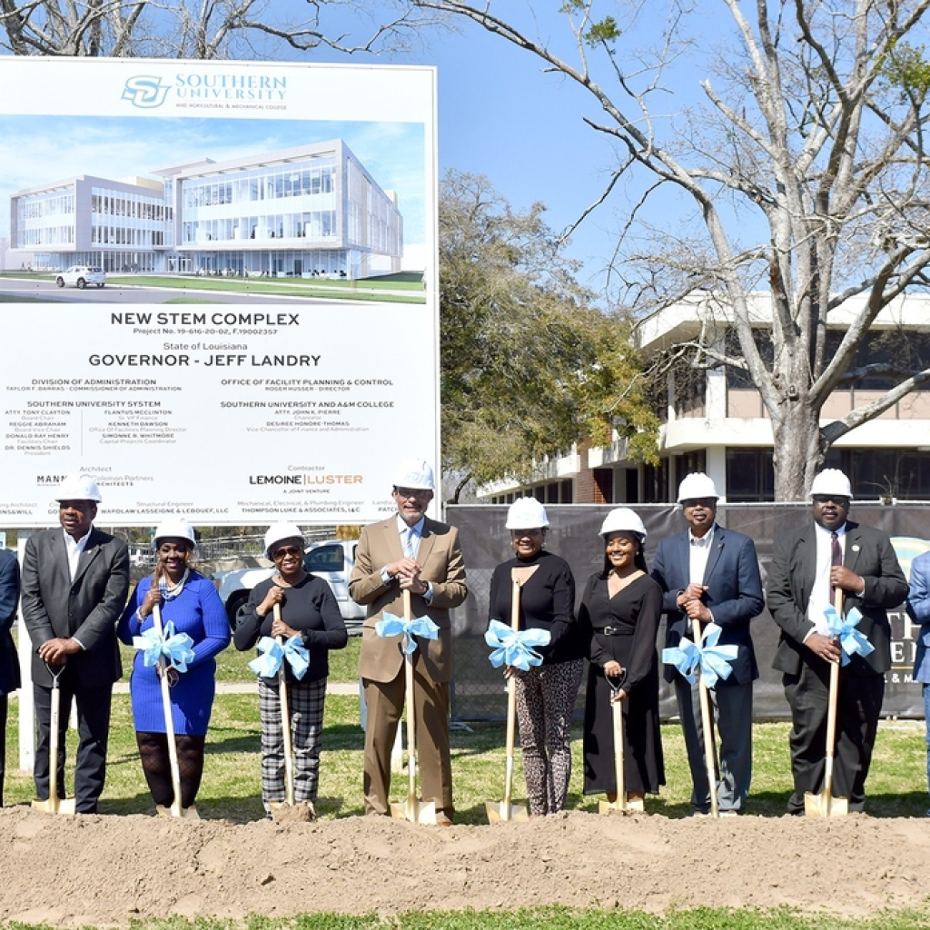 Group of people at a groundbreaking ceremony with shovels and a construction sign.