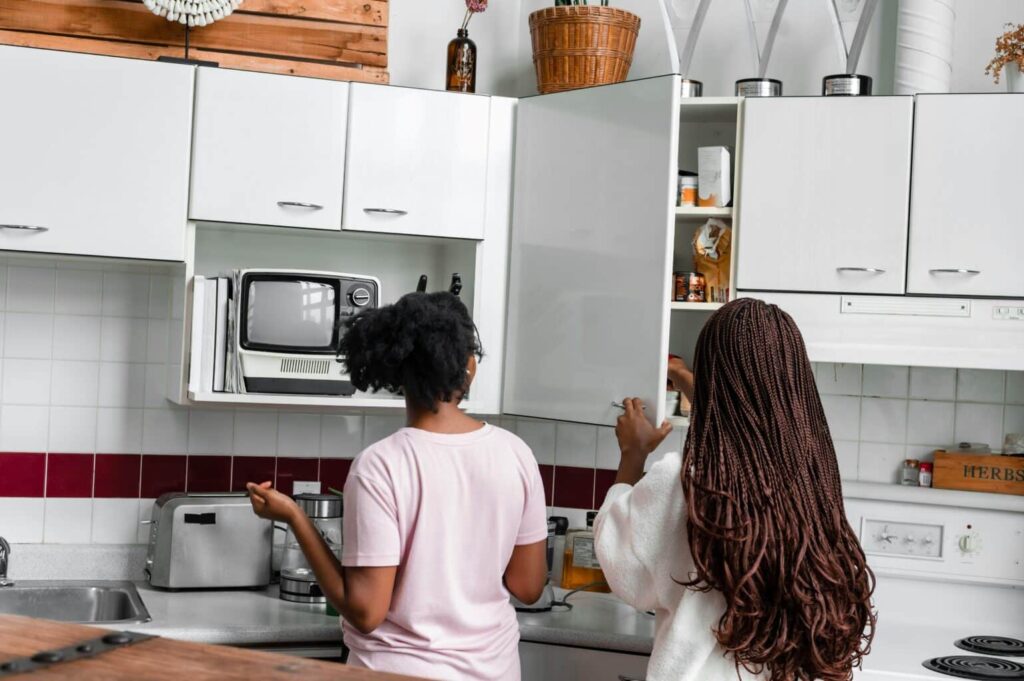 Two ladies looking into their cabinets