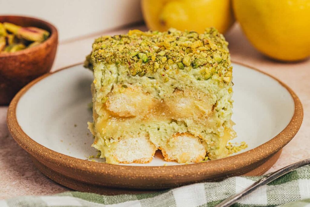 A slice of lemon pistachio tiramisu on a plate.