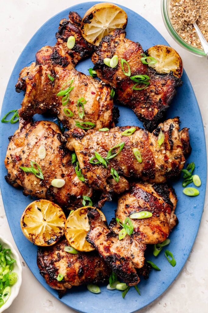 grilled jerk chicken thighs on blue oval platter