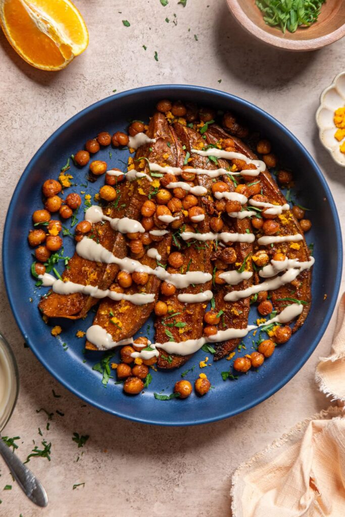 tahini butter sauce over roasted sweet potatoes and crispy chickpeas in a blue bowl.