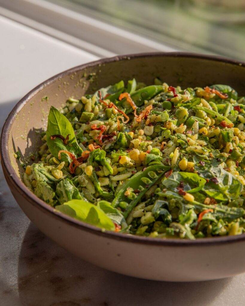 Large bowl filled with orzo pasta salad that is tossed in a creamy basil vinaigrette.