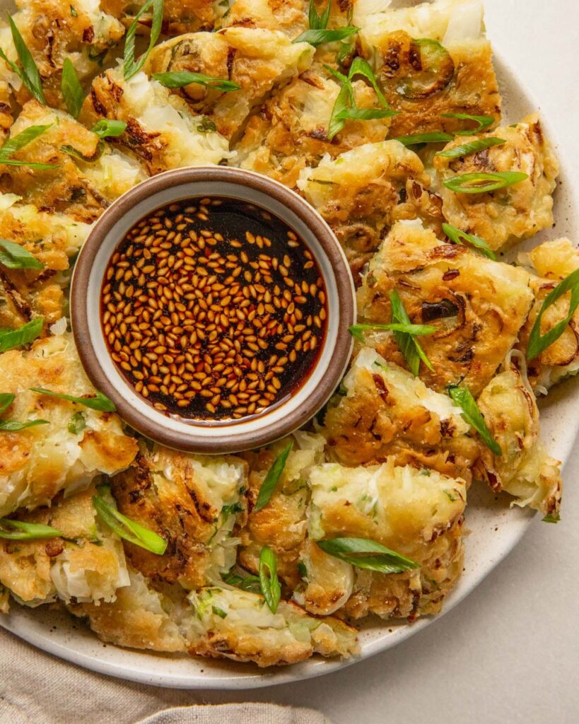 Tofu Vegetable Pancakes – Plant Based RD Close up of a plate filled with cut up veggie pancakes arranged around a bowl of dip.