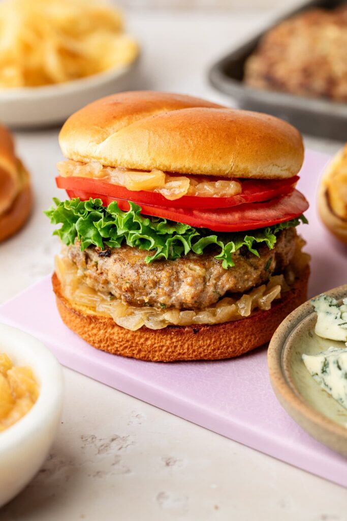 blue cheese turkey burgers with lettuce and tomato on purple cutting board
