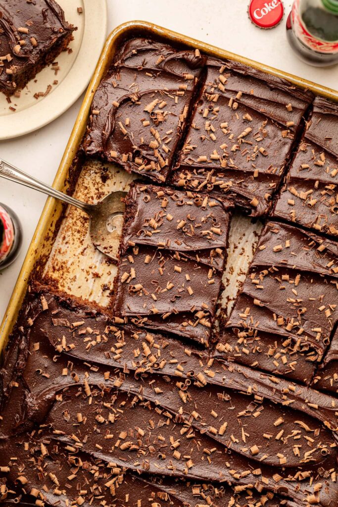 sliced cola cake in sheet pan with serving utensil