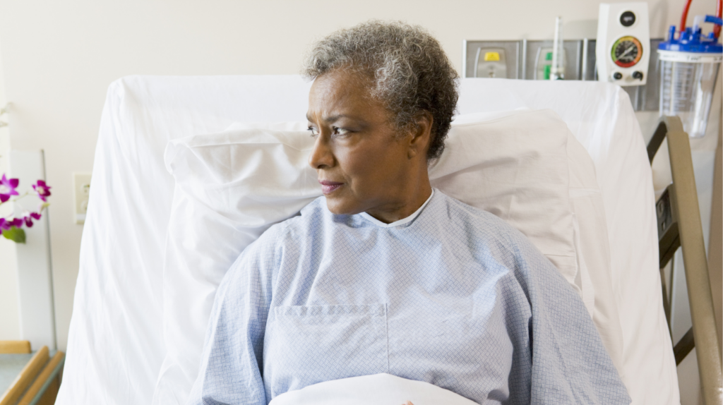 Senior Black woman in a hospital bed looking out the window