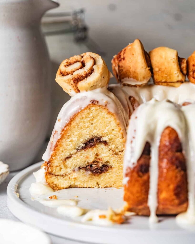 cinnamon roll bundt cake sliced on a cake plate so that you can see the double layers of cinnamon swirl.