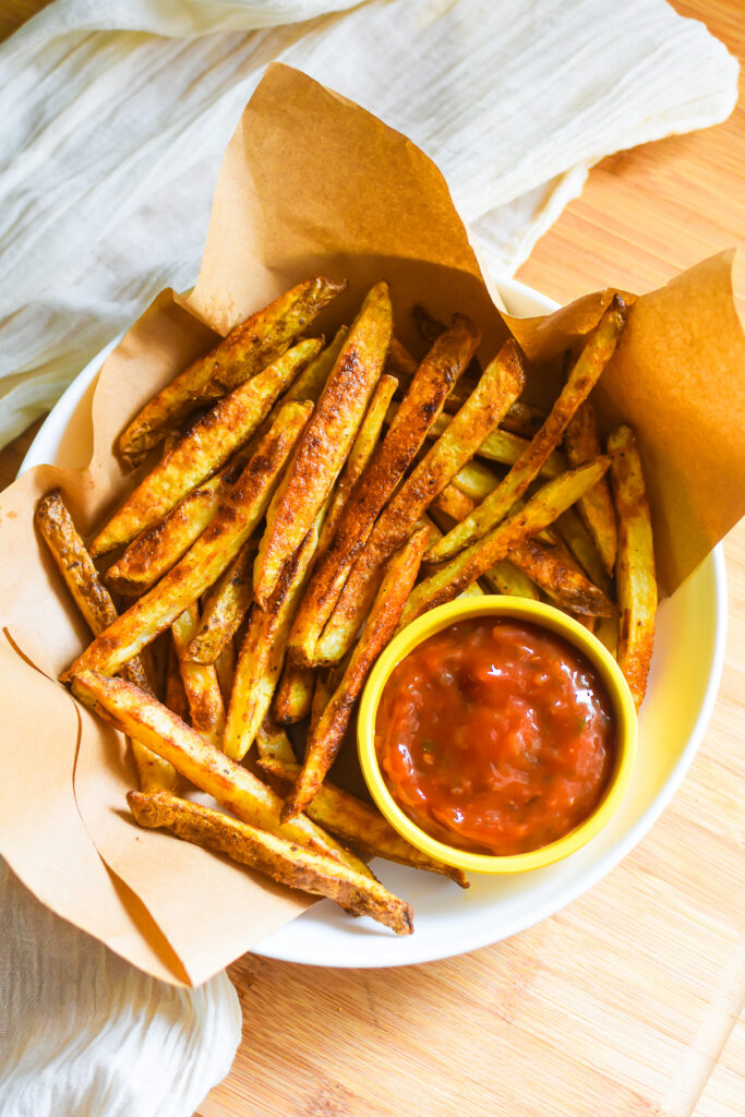 Crispy Oven Baked French Fries with Pickle Ketchup the best oven baked french fries served on a plate lined with brown butcher paper with a ramekin of homemade pickle ketchup.