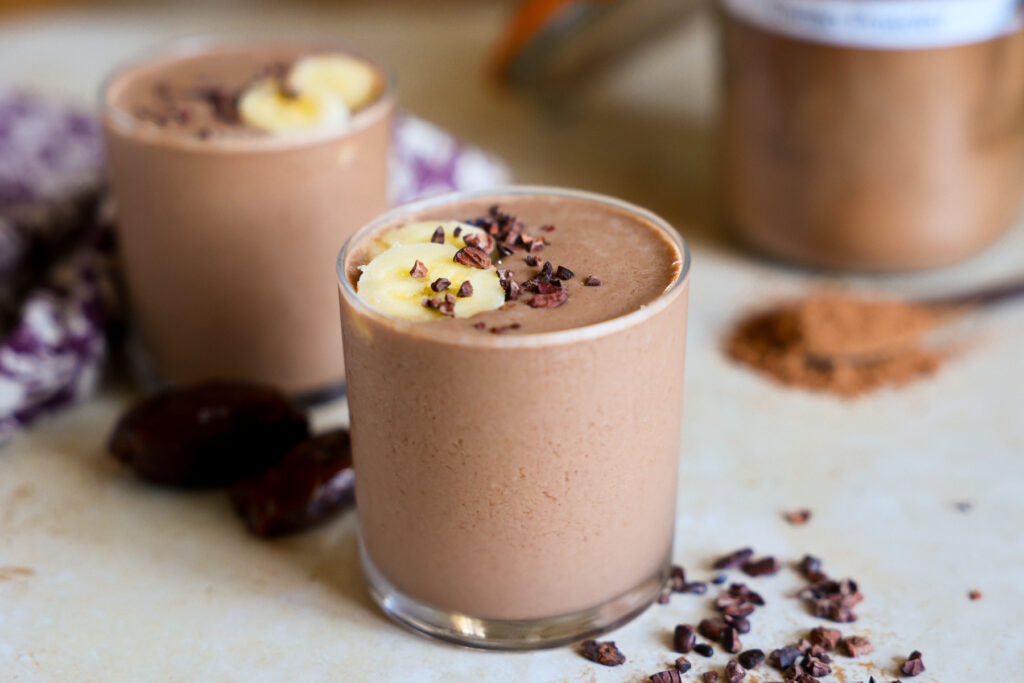 Creamy cacao smoothies in glasses and garnished with banana.