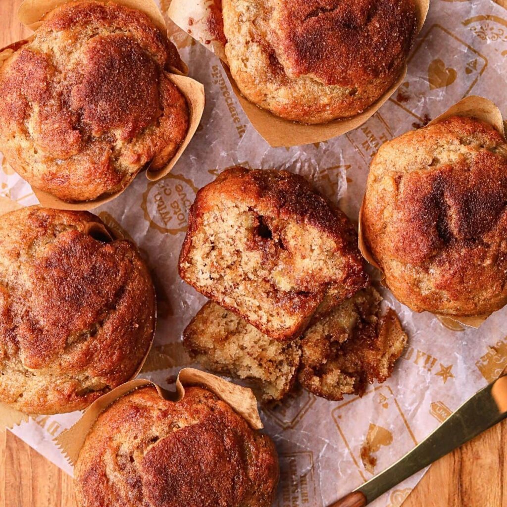 Cinnamon Swirl Banana Muffins – Pink Owl Kitchen Cinnamon swirl banana muffins on a wooden board.