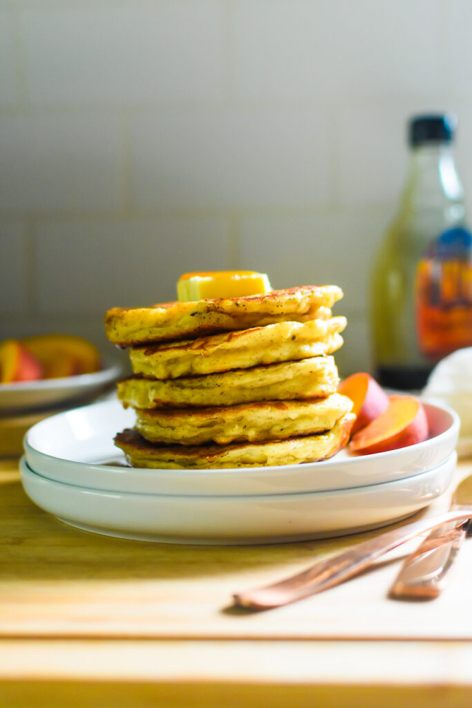 Thick and Fluffy Greek Yogurt Pancakes stack of the best, fluffiest Greek yogurt pancakes on white saucers topped with a thick pat of butter and amber-colored maple syrup.