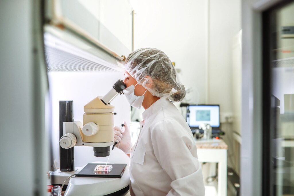 High Fertility Costs Push Americans Abroad for IVF Treatment A photo of an embryologist in an IVF laboratory using a microscope while working with a pipette and an embryo in a petri dish.