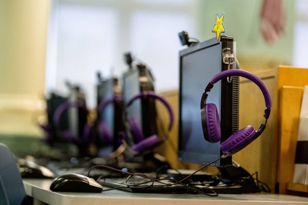 A row of computer stations with headphones in a classroom.