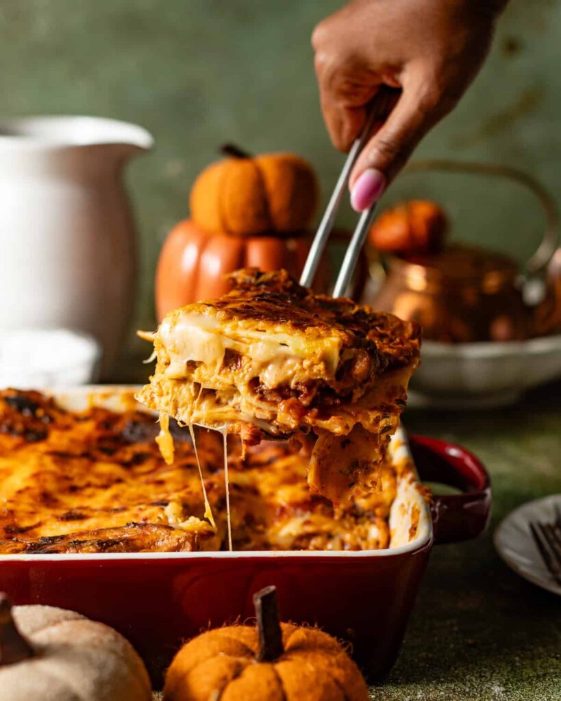 a spatula scooping pumpkin lasagna out of a baking dish to show the cheese pull.