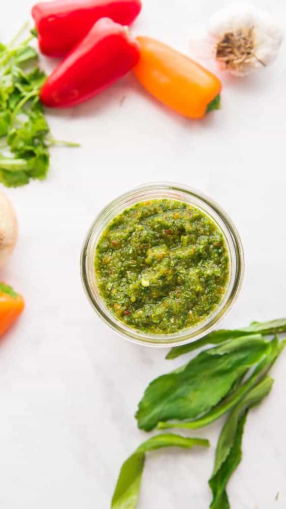 Puerto Rican Sofrito- Authentic Culantro Cooking Base A jar of Sofrito is surrounded by the ingredients used to make it.