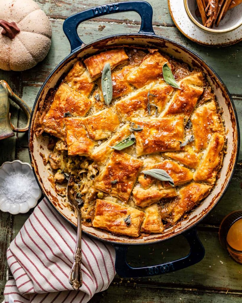 Chicken Pot Pie with Puff Pastry chicken pot pie with puff pastry in a pan with a spoon scooping out the smooth pot pie filling.