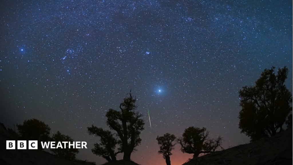 A meteor strikes across a dark blue star-filled night sky