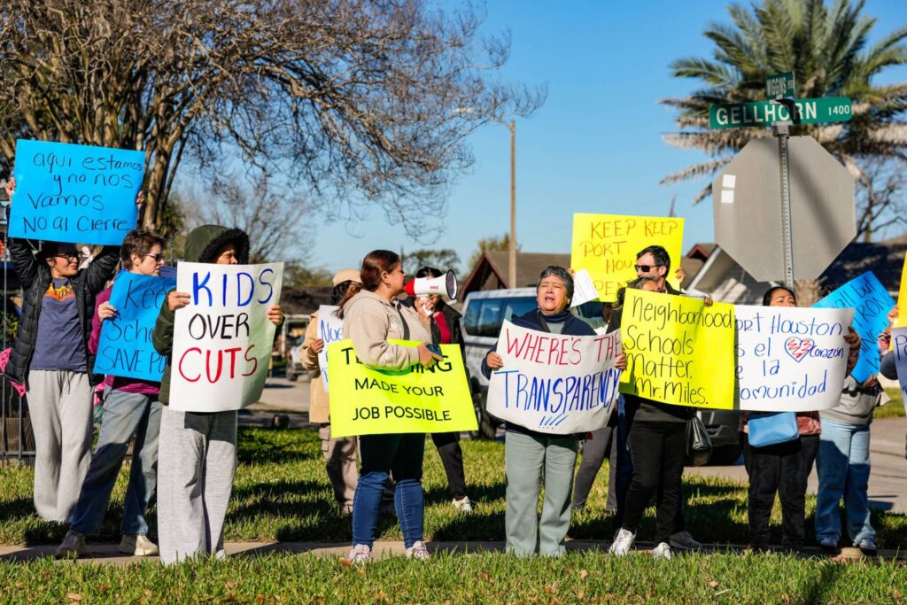 Merging School Districts Was Supposed to Save Taxpayers Money. It Didn’t, a 20-year Study in Arkansas Found Parents gather on grass holding signs of protest